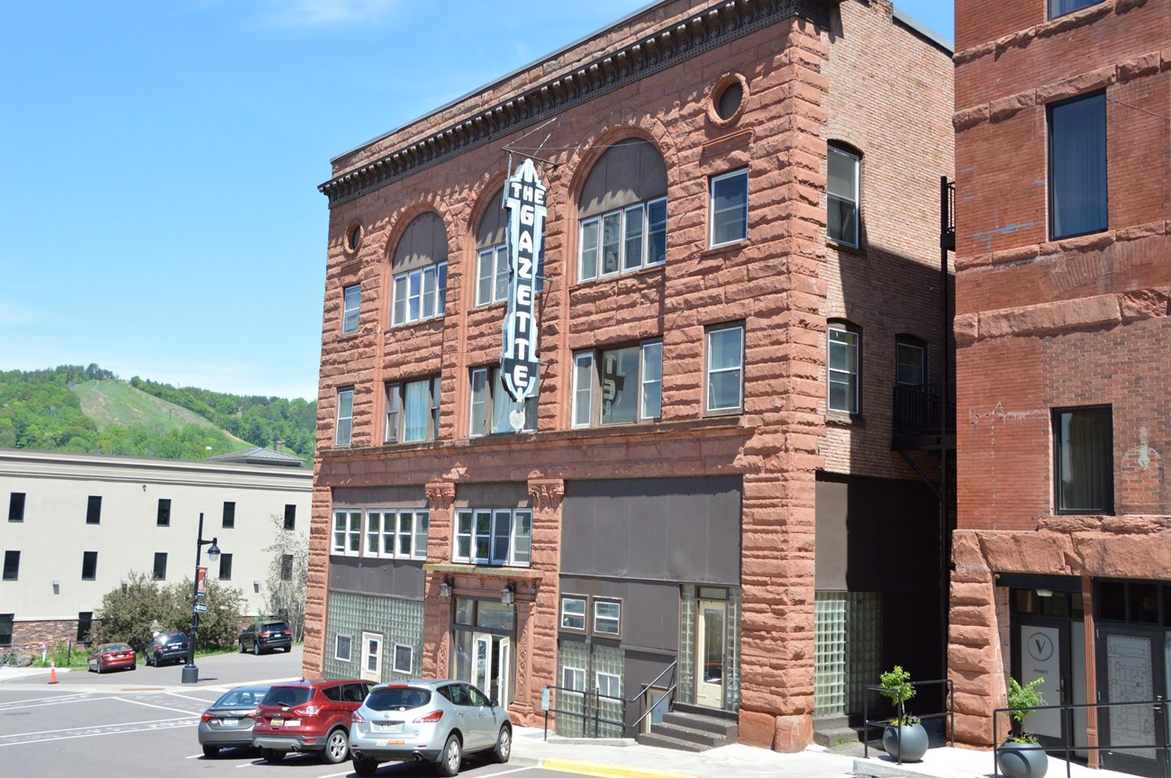 A historic back and white photo of a three-story brick and sandstone building in Calumet, MI