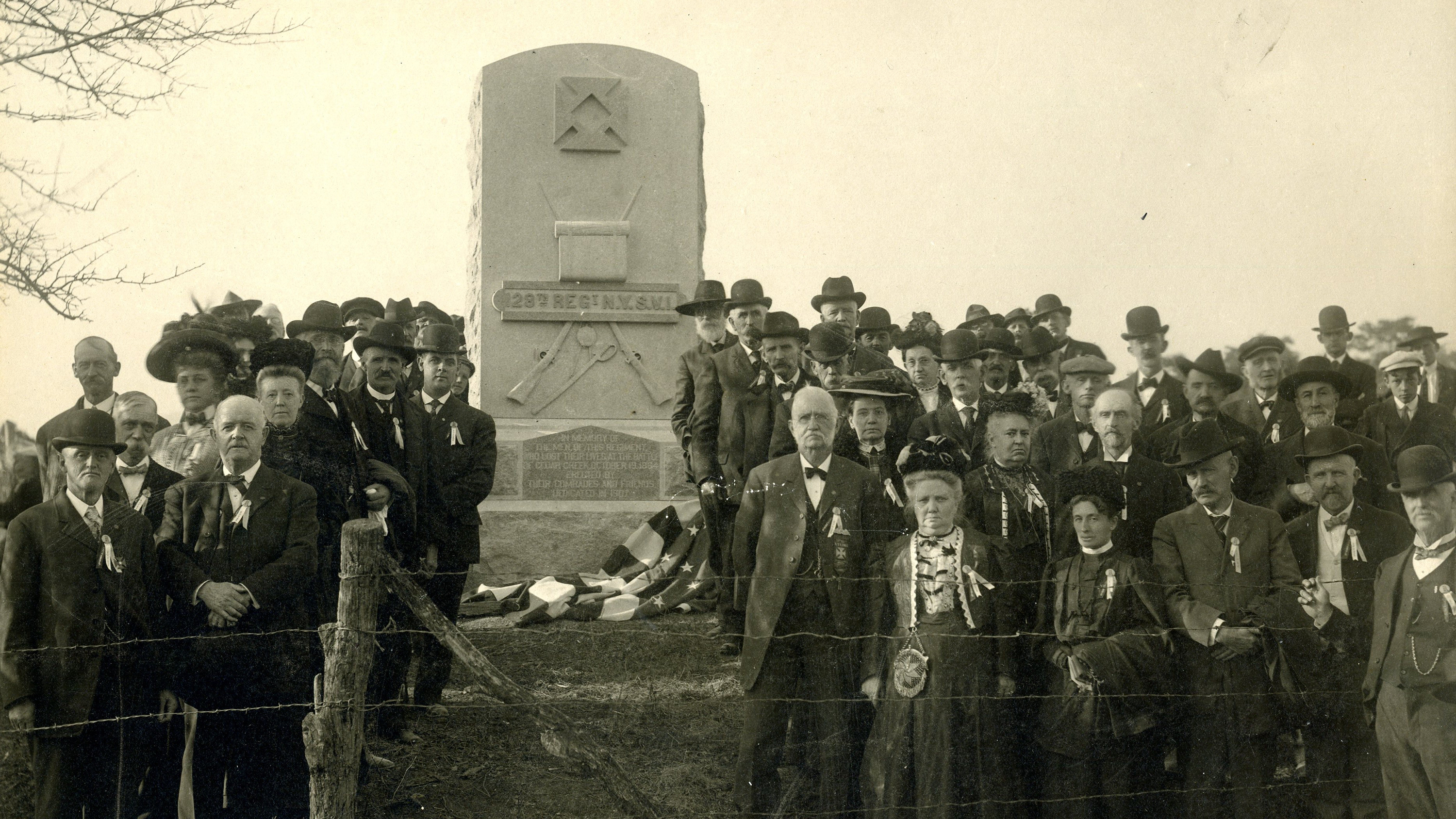 A tall stone monument displaying several military symbols including the Nineteenth Corps Badge, crossed rifles, a knapsack, and a sword. The inscription states,  "128th Regt N.Y.S.V.I."