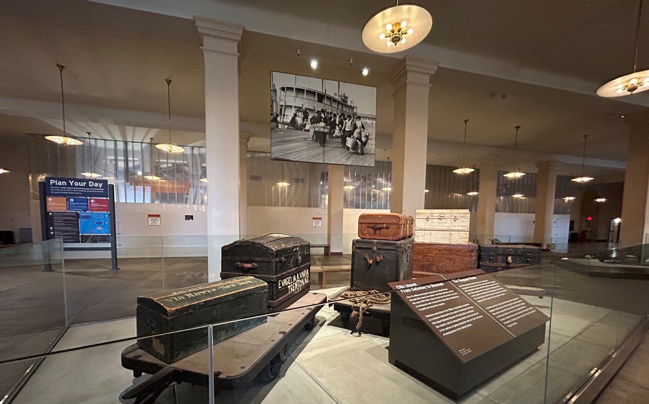 The Baggage Room at Ellis Island before construction. A trolly with historic baggage is in the foreground.