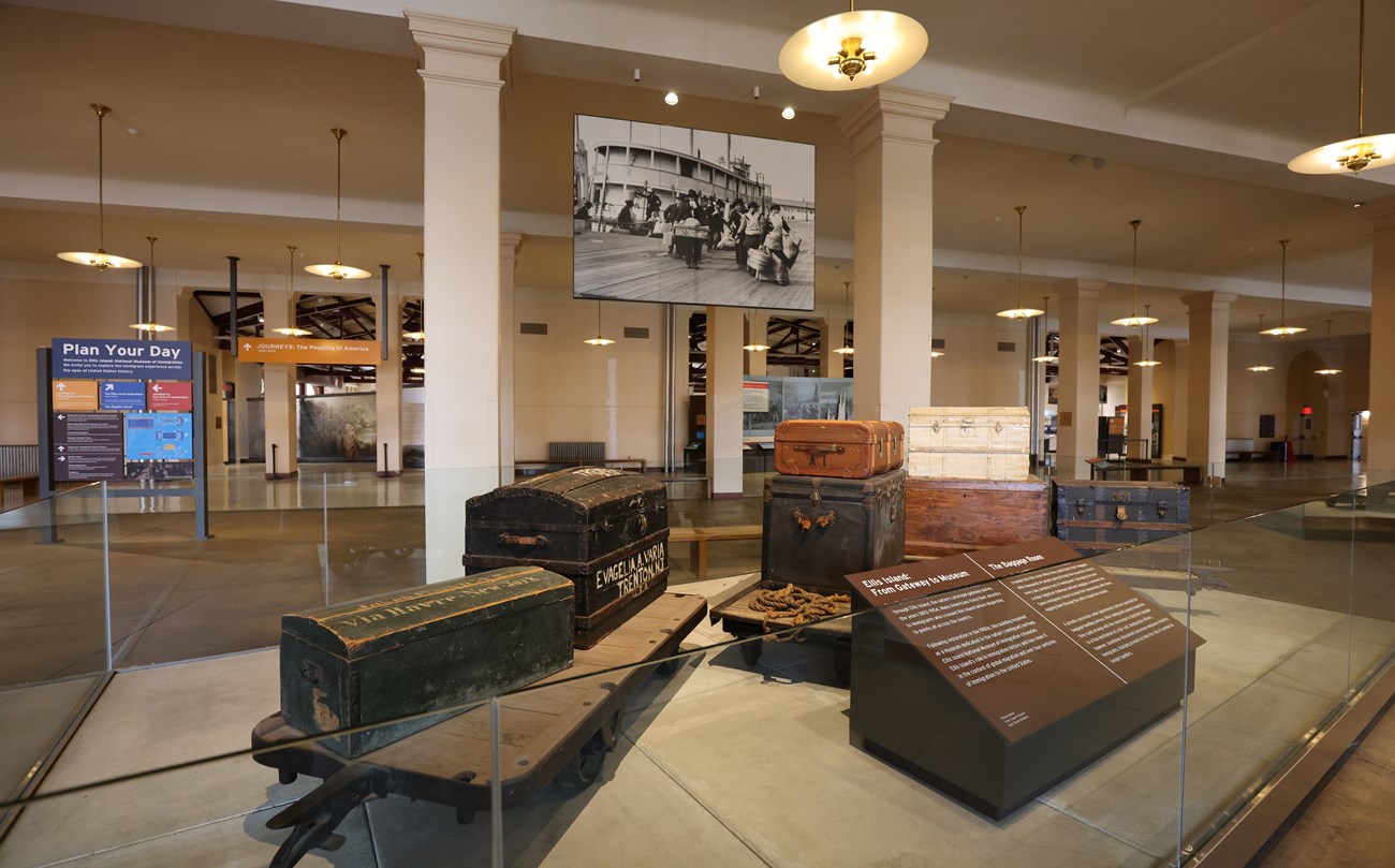 The Baggage Room at Ellis Island before construction. A trolly with historic baggage is in the foreground.