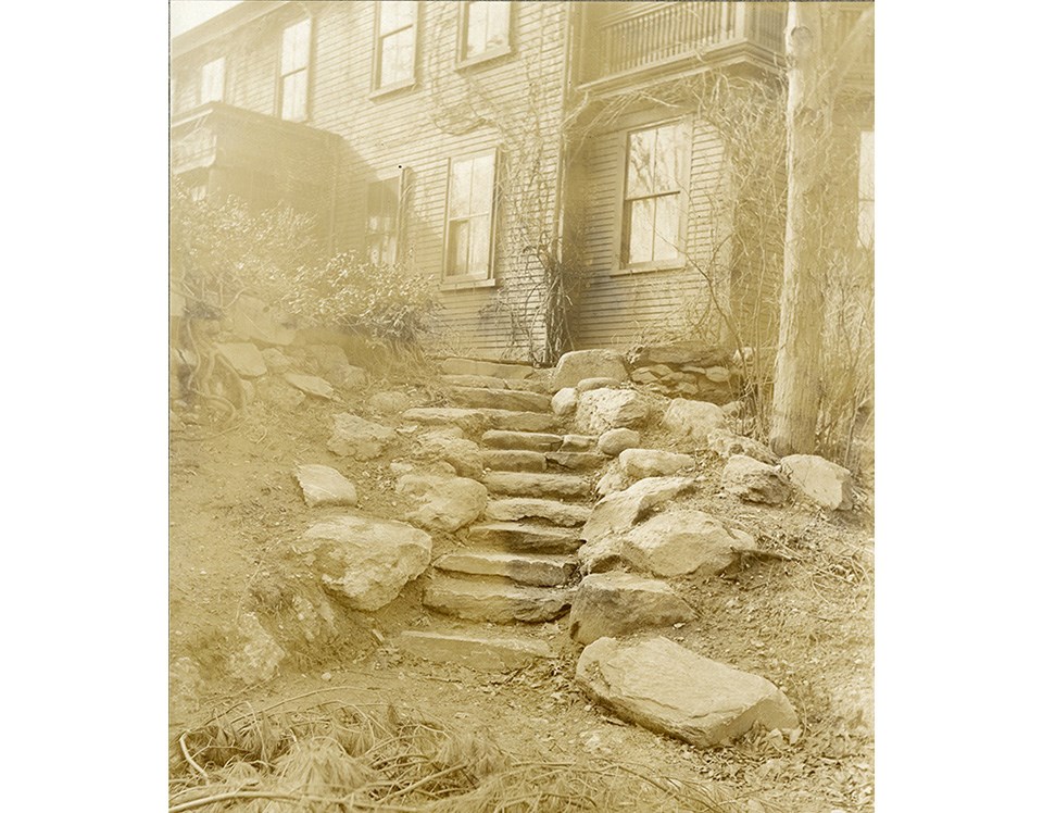 Gently-curving stone steps lead toward a two-story house, 1933.