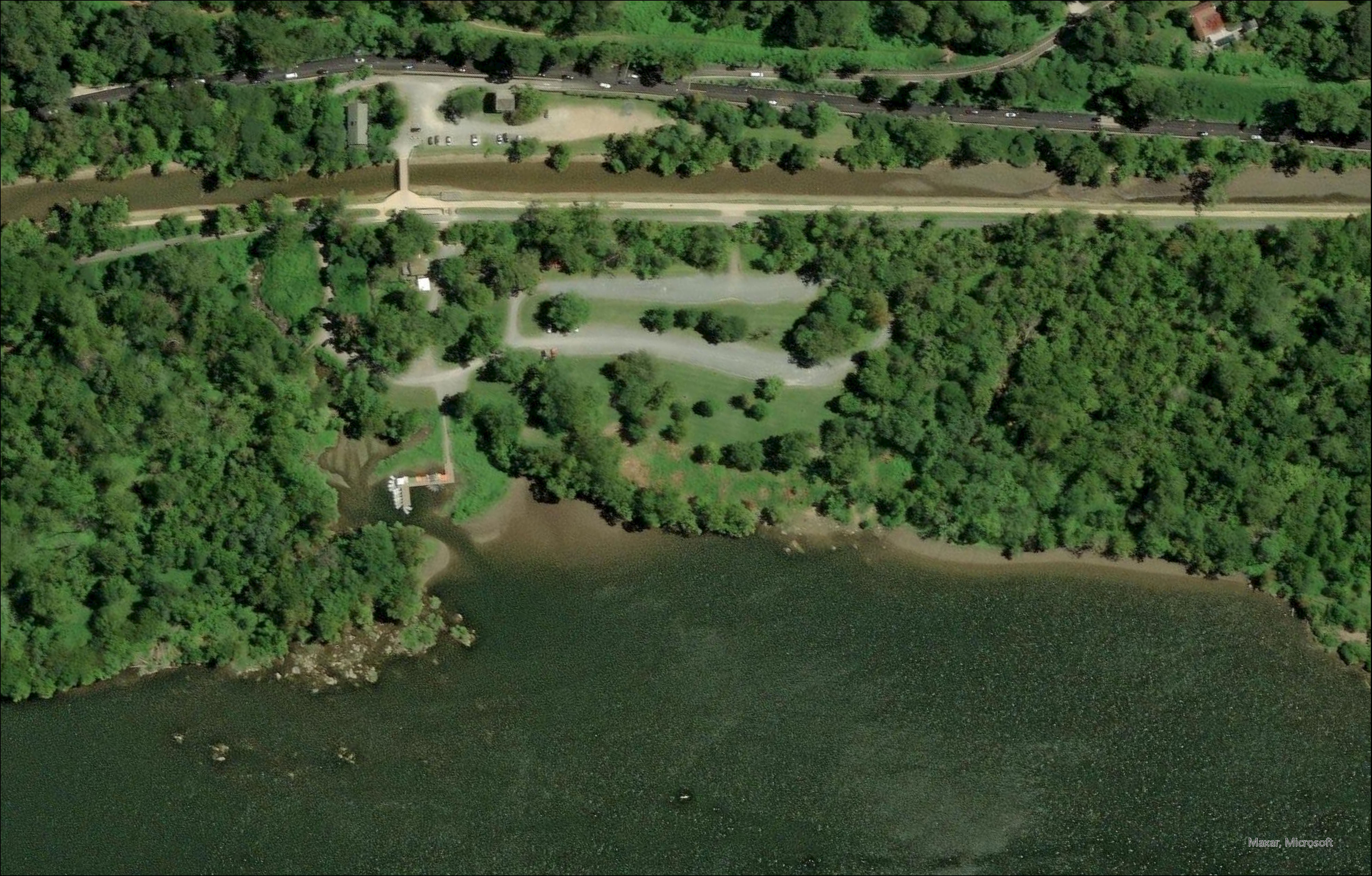 Black and white aerial photo of Fletcher’s Cove that shows a wide worn area in place of the previous dirt path from the boathouse to the Potomac River.  The Potomac River is at the bottom of the image and the Chesapeake and Ohio Canal is towards the top.