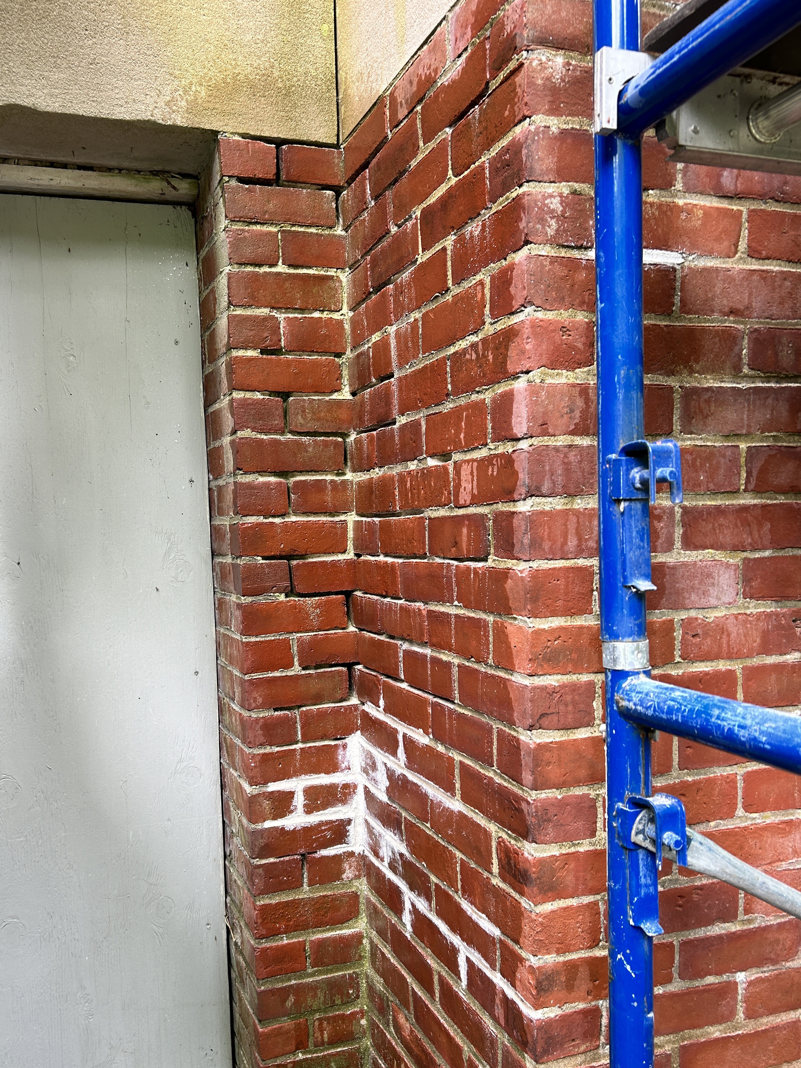 A corner where two old brick walls meet. Much of the mortar has crumbled, leaving empty spaces between the bricks.