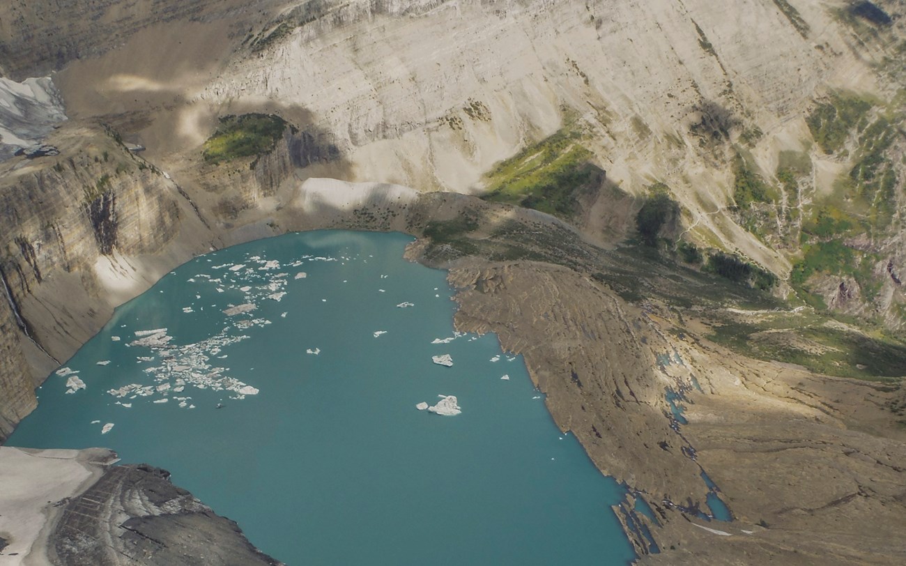 a bright blue lake with ice floating in it