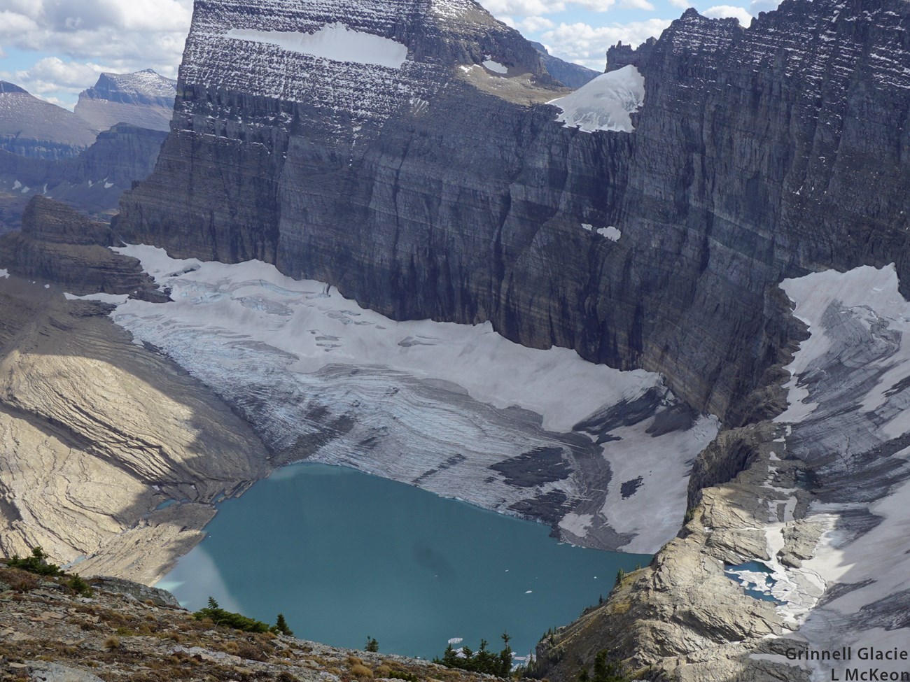 a mountain with a glacier below it and a lake in front of the glacier