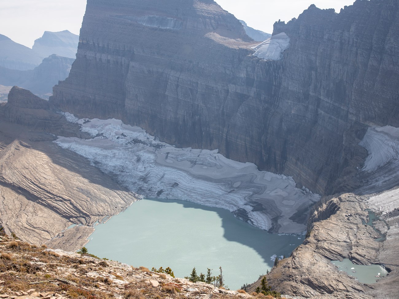 a mountain with a glacier below it and a lake in front of the glacier