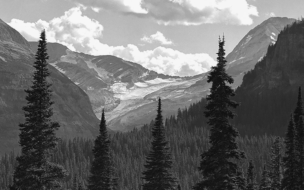 A fuzzy black and white landscape photograph of a glacier with a mountain on the right.