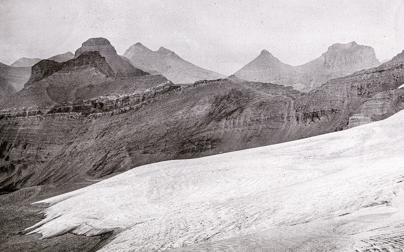 A wide angle image of a dry seeming alpine landscape with mountains in the background.