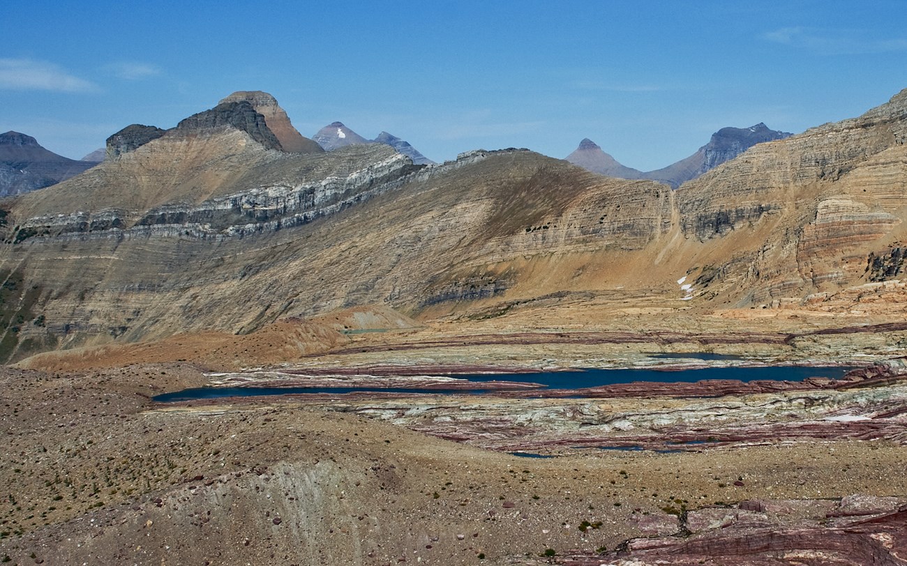 A wide angle image of a dry seeming alpine landscape with mountains in the background.