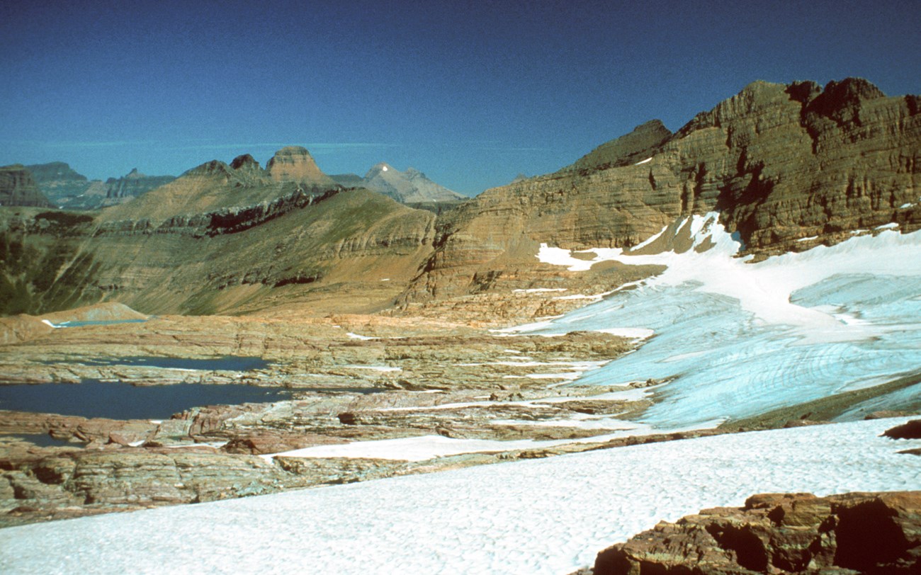 A wide angle image of a dry seeming alpine landscape with mountains in the background.