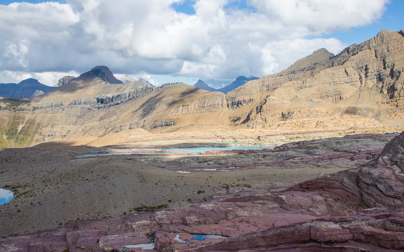 A wide angle image of a dry seeming alpine landscape with mountains in the background.