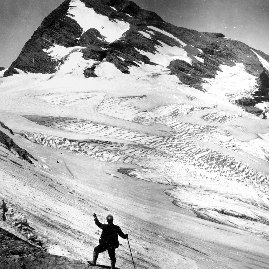 A square glacier landscape with a large mountain in the background and a person in the foreground.