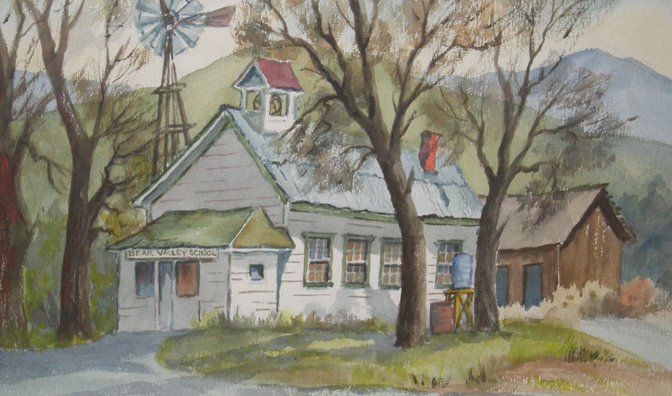 A group of students stand in a grassy area near trees in front of a school building with a porch and bell