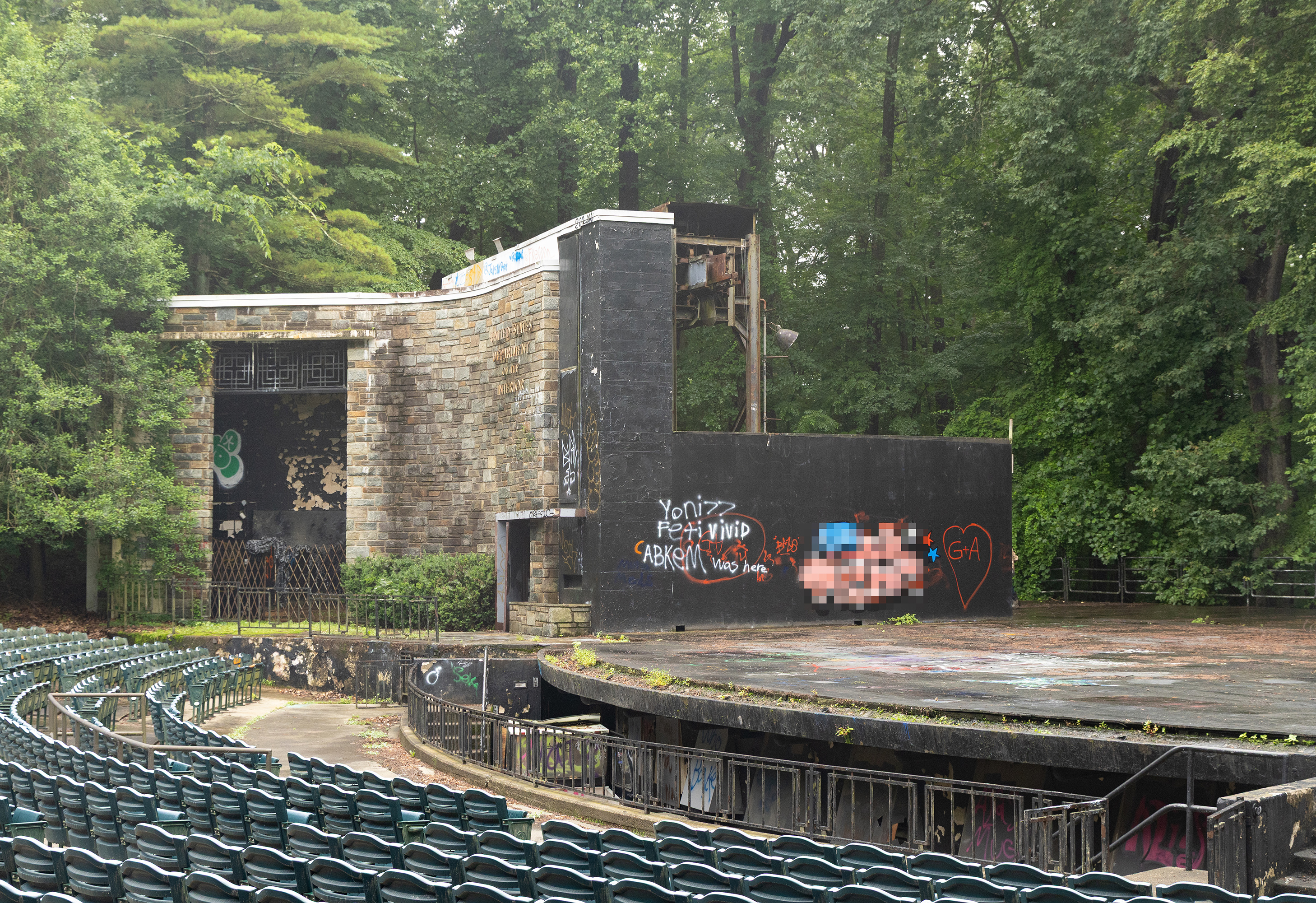 Seating at the Carter Barron Amphitheater with colorful graffiti on the stage walls.