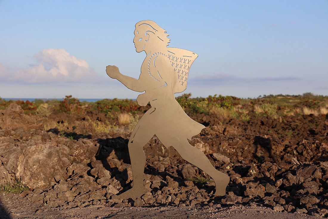 Silhouette statue of a kukini or Hawaiian runner running through a lava field