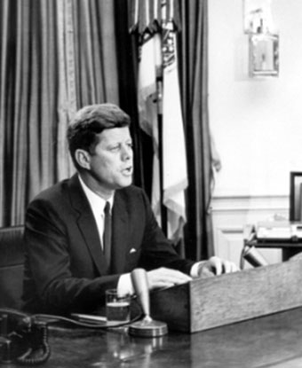 B&amp;W photo of JFK seated at desk with microphone addressing nation