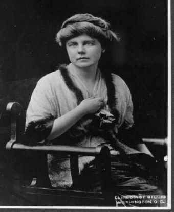 Studio Portrait Lucy Burns seated in wooden arm chair facing right 