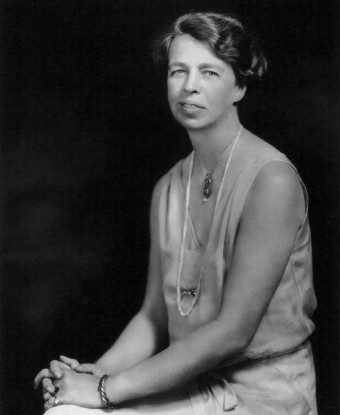 A seated woman (Eleanor Roosevelt) wearing a sleeveless gown and a string of pearls.