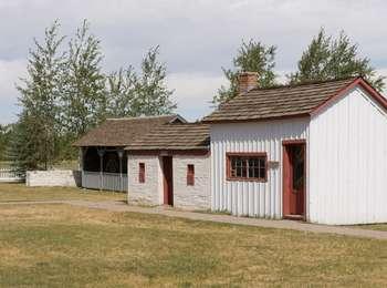 Historic buildings with red trim and wood roofs in a landscape of grass meadows and small, scattered trees