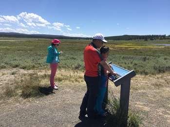 Three visitors learning about the peaks of the Gallatin Range