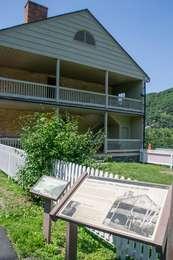  Wayside in front of white building with balcony on the second floor and a red chimney.