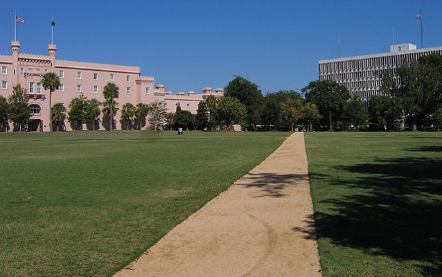 Green law with dirt path. Buildings in background. 