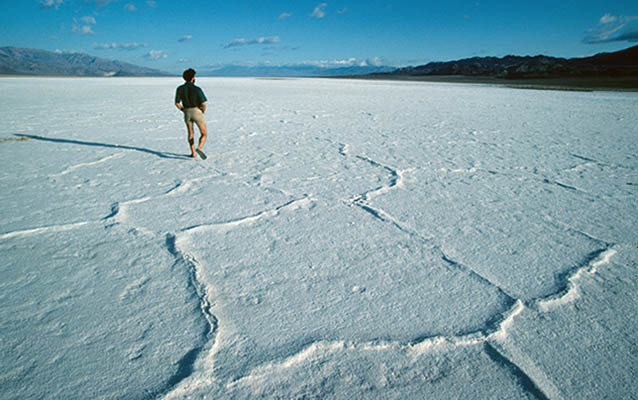 An expansive salt flat, devoid of obvious life, with distant desert mountains. 