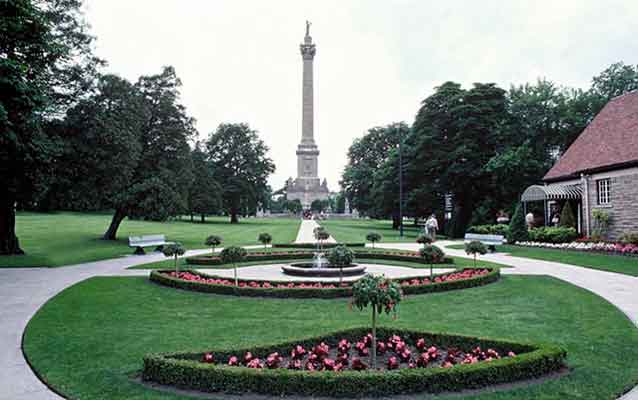 The yard at Queenston Heights. Circular yard with sidewalk and landscaping and a tall statue.