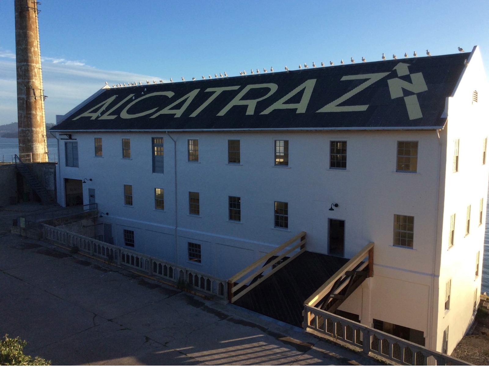 A four story building with scaffolding, flaking paint and moss-covered roof.