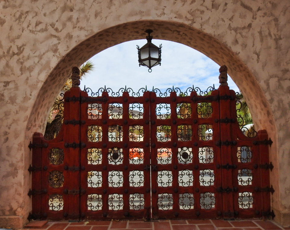 Two men talk outside a gate with three dogs near them.