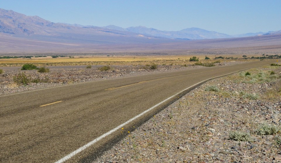 Dirt road with car in desert.