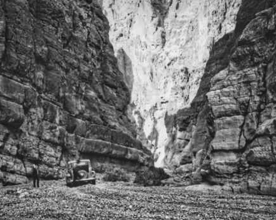 An old car driving through narrow canyon.