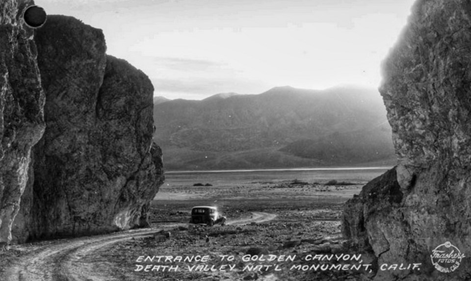 A car drives out of a canyon with a broad valley beyond.