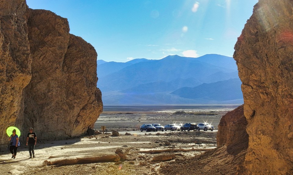 A car drives out of a canyon with a broad valley beyond.