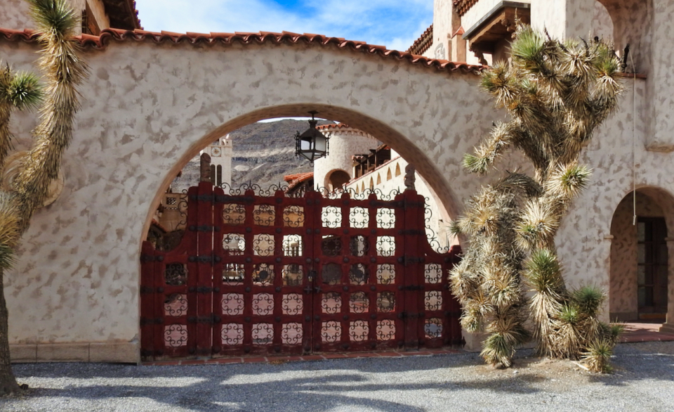 A group of men stand in front of arched entrance to buildings.