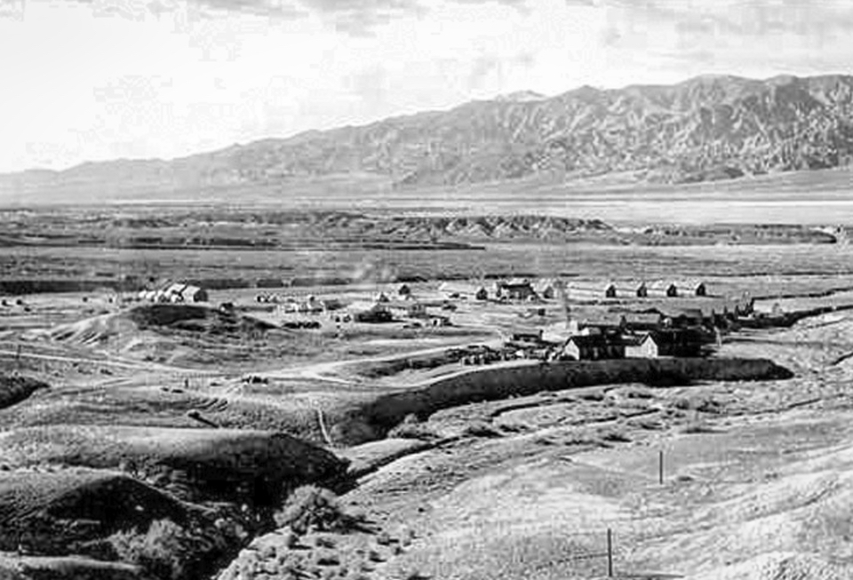 Buildings visible across desert wash with mountains in background.
