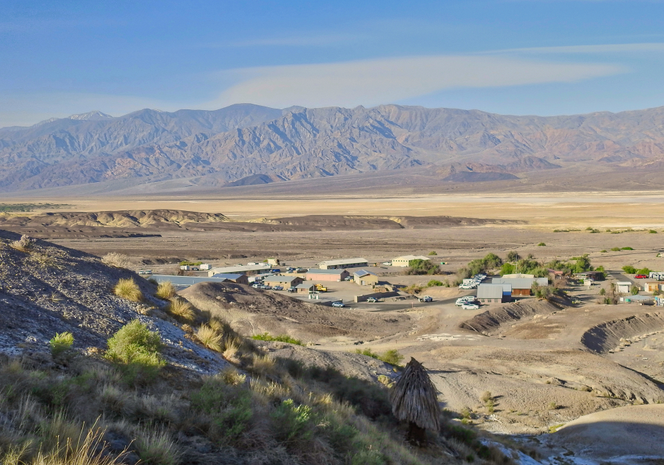 Buildings visible across desert wash with mountains in background.