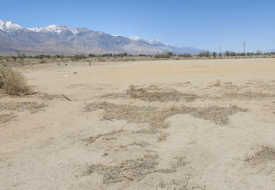 Spectators watch a baseball game with mountains in background.