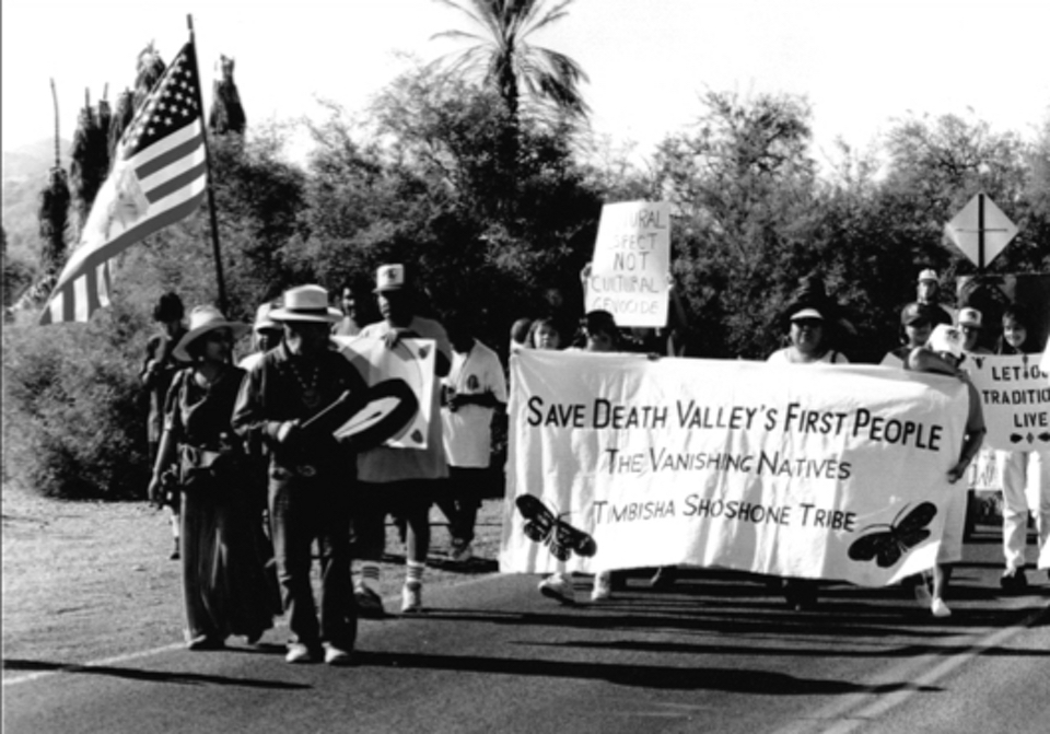 People with flags and banners march on the street.