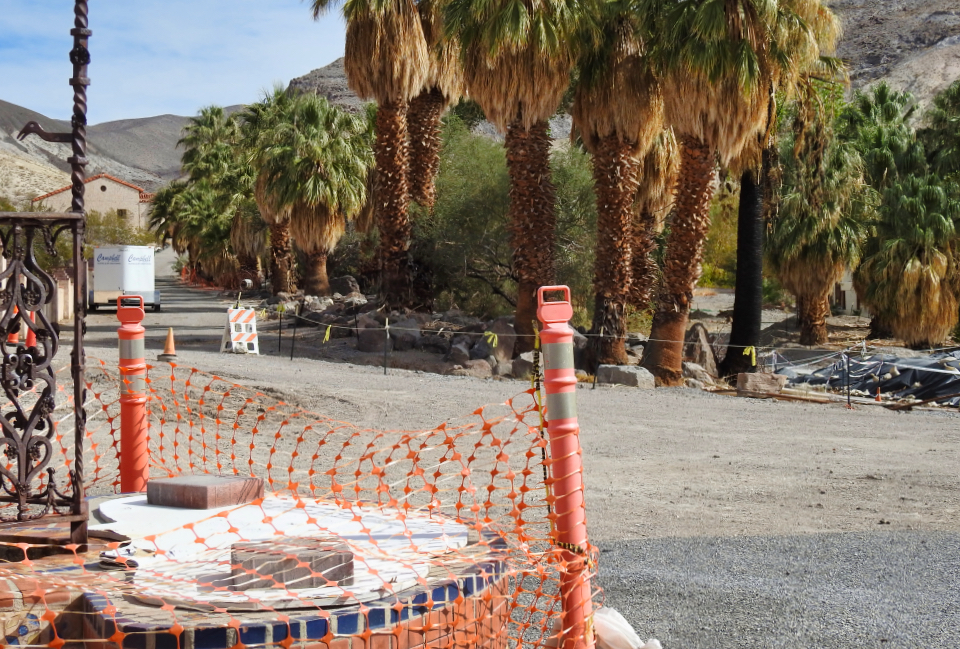 Two men in front of a fountain with hills in background.