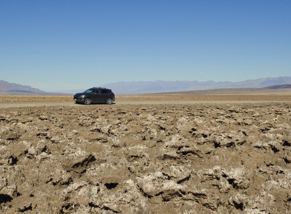 Men and three old cars crossing very rocky landscape.
