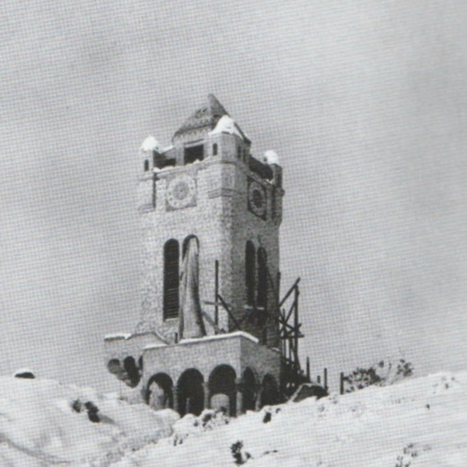 A clock tower with snow surrounding it.