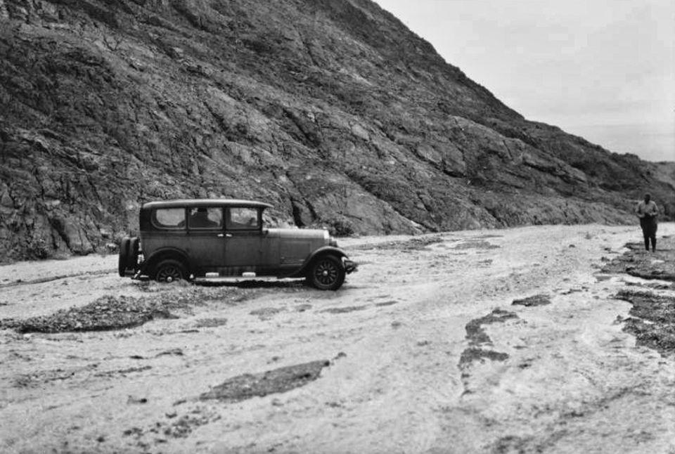 A car is stuck in floodwaters with man on dry land.