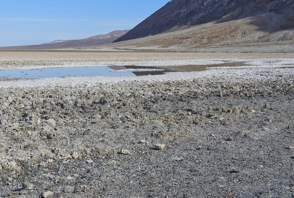 Sign with pool and hillside behind covered in snow.