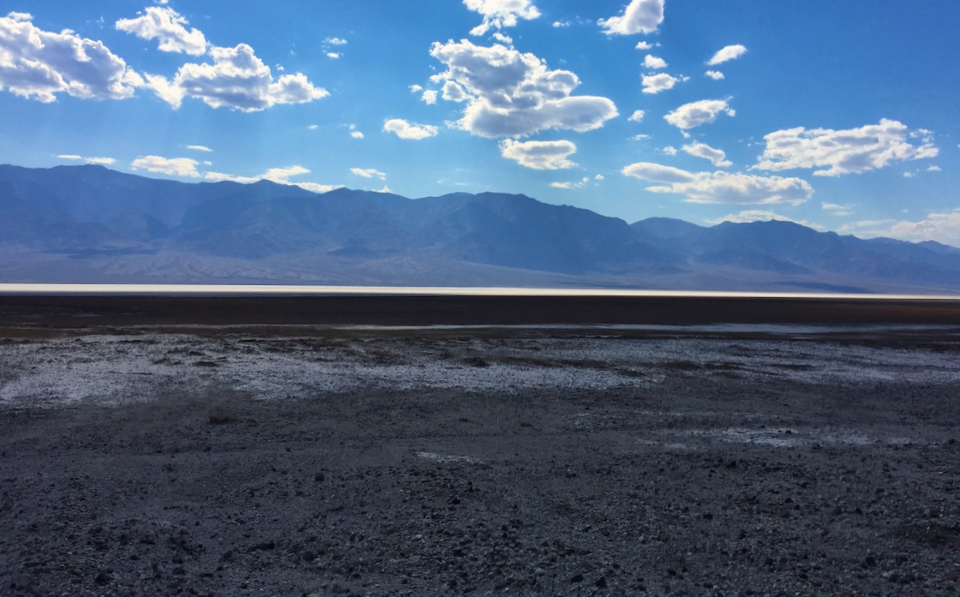 A painting with a red line at the bottom and mountains in the background.