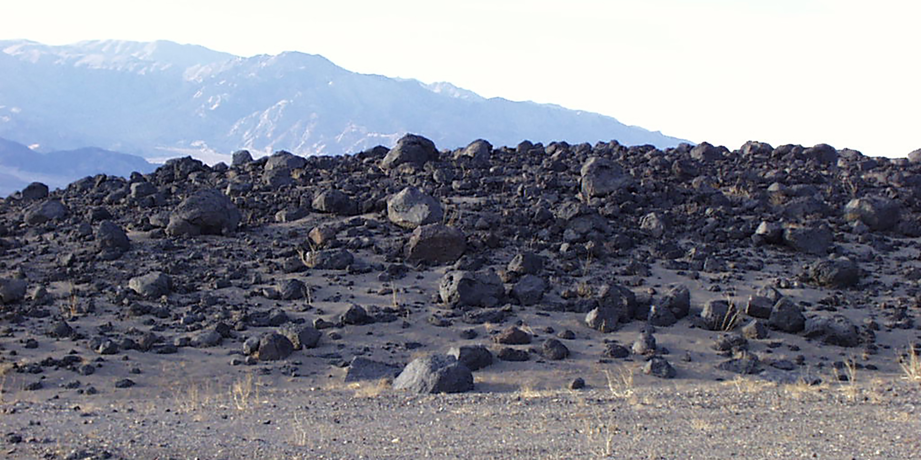 barren, rocky expanse, with a scattering of black boulders and smaller rocks covering the ground.