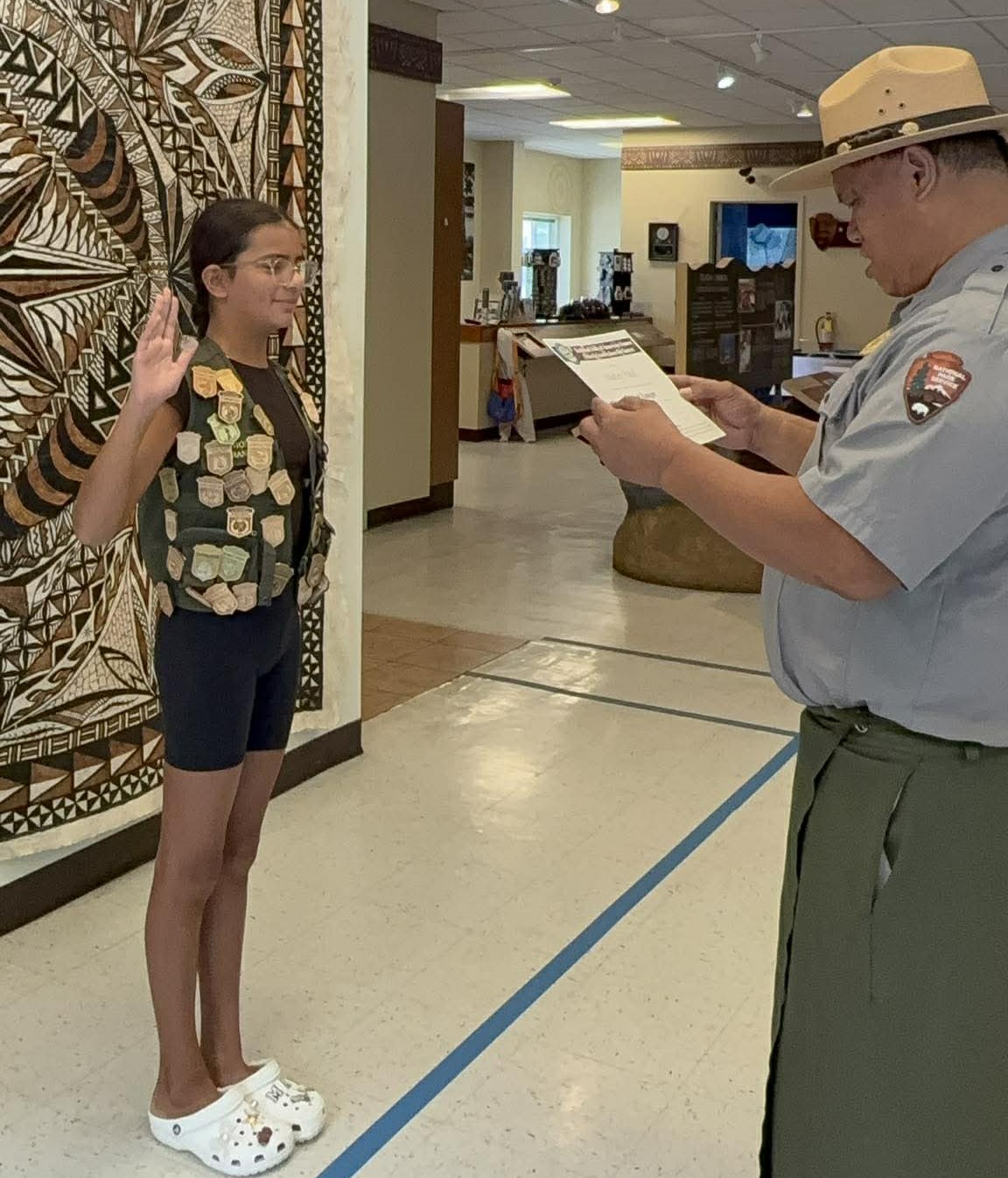Indoors; Inframe five children and one adult working on books in exhibit area.