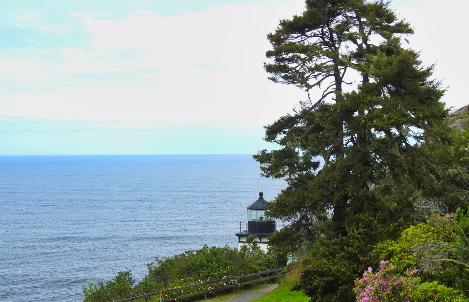 Naval ships lined up on ocean passing lighthouse