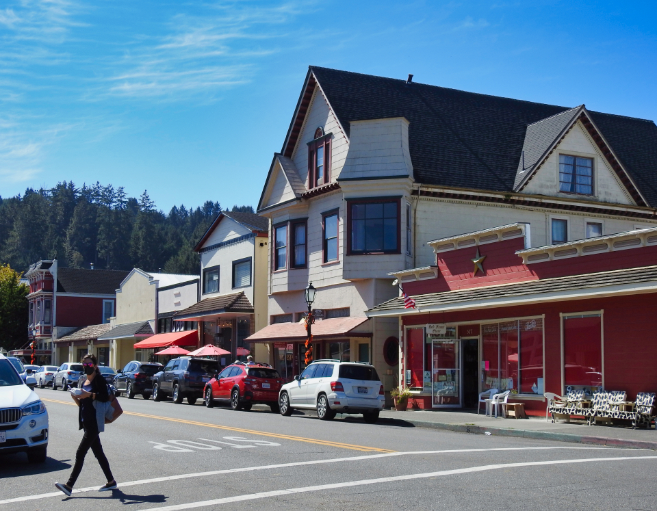 Old automobiles on dirt street in front of buildings