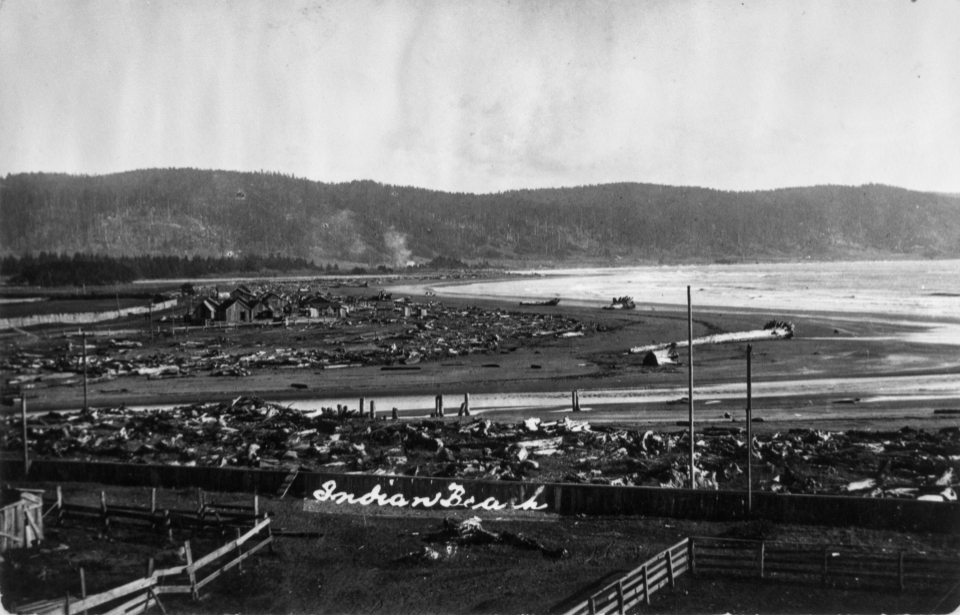Ocean bay and beach with mountains in background, buildings in foreground.